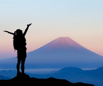 Woman reaching up with mountain in background